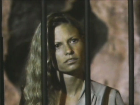 Woman's head and shoulders behind bars. Bars form shadows on her face.